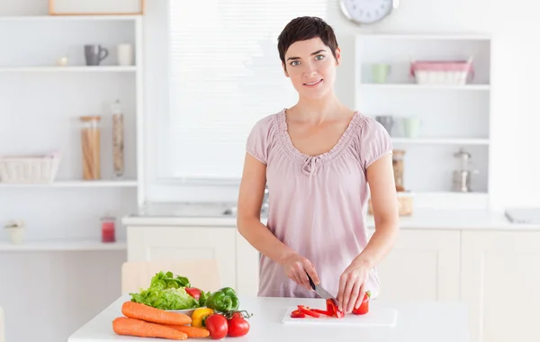 Усміхнена жінка нарізає овочі — стокове фото