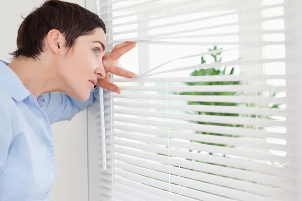 Woman peeking out a window — Stock Photo, Image