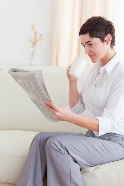 Portrait of a woman drinking coffee while reading the news — Stock Photo, Image