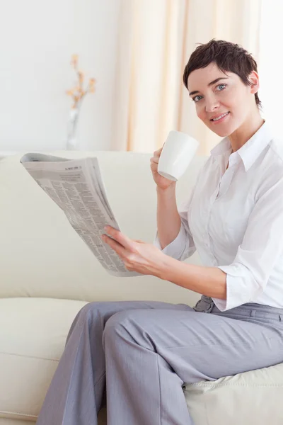Retrato de uma mulher com um copo lendo as notícias enquanto olha para — Fotografia de Stock