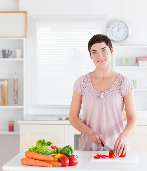 Glimlachende vrouw die groenten snijdt — Stockfoto