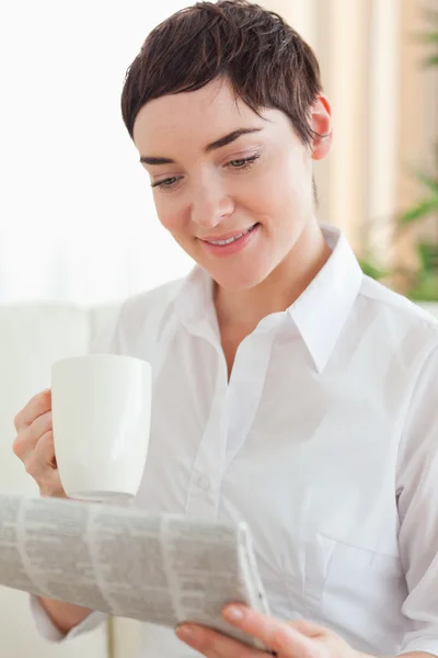 Mulher bonito com uma xícara e um jornal — Fotografia de Stock