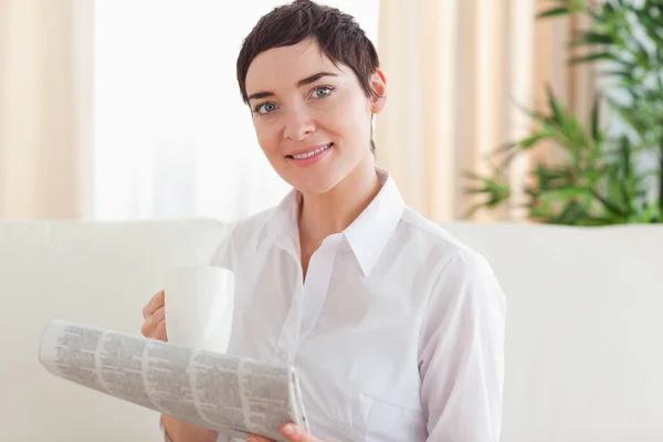 Portrait of a Brunette woman with a cup and a newspaper — Stock Photo, Image