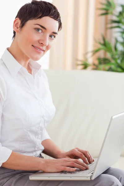Brunett kvinna med en laptop som ser in i kameran — Stockfoto