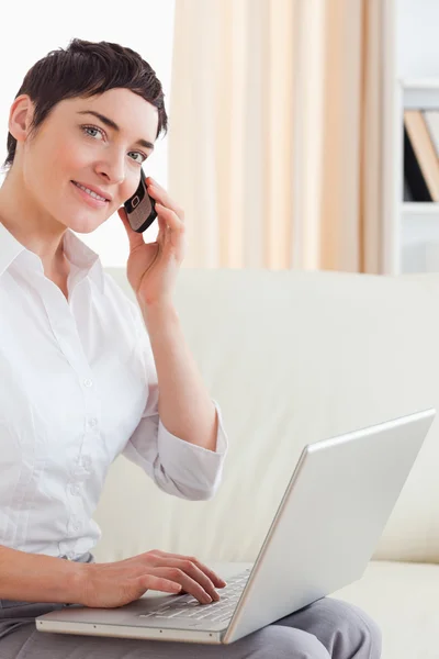 Mulher de cabelos curtos com um laptop e um telefone — Fotografia de Stock