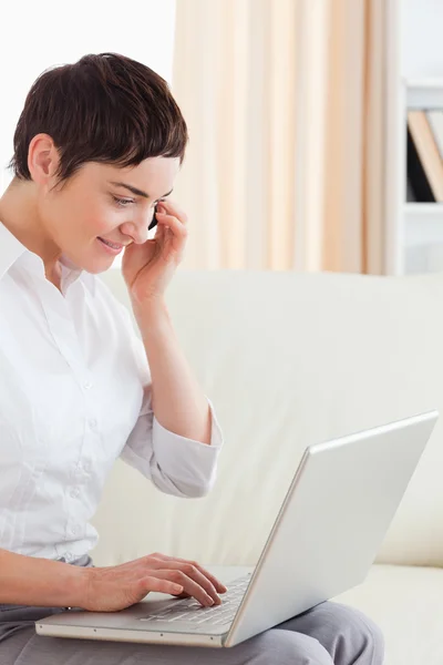 Charming Short-haired woman with a laptop and a phone — Stock Photo, Image