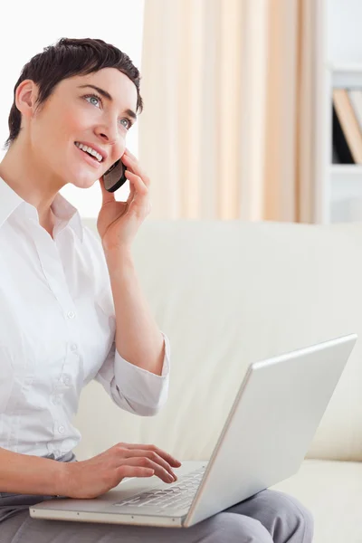 Bir dizüstü bilgisayar ve telefon ile büyüleyici kadın — Stok fotoğraf