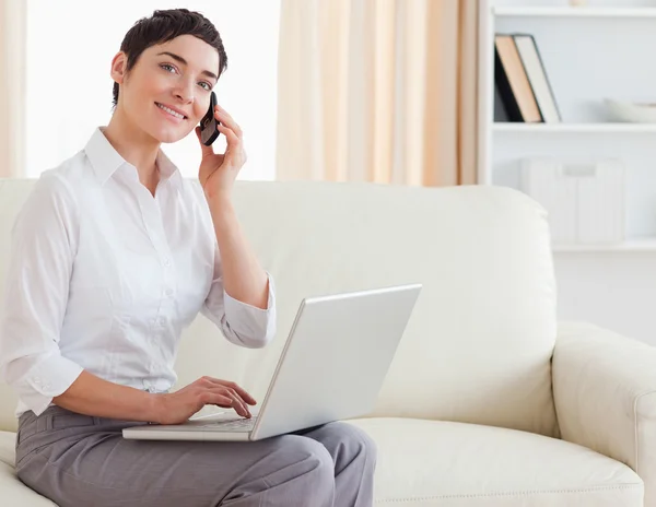 Prachtige brunette vrouw met een laptop en een telefoon — Stockfoto