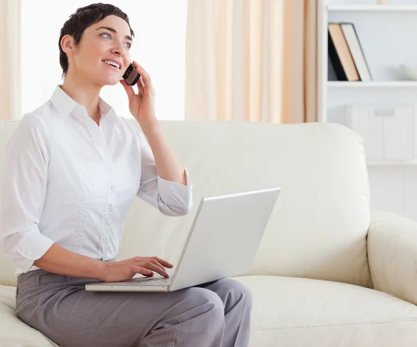 Gorgeous short-haired woman with a laptop and a phone — Stock Photo, Image