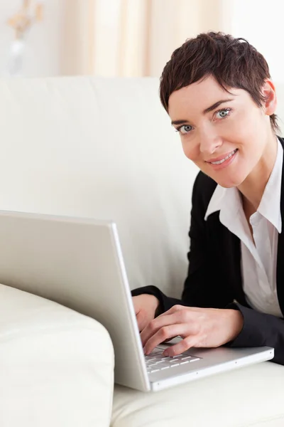 Close up of a brunette Businesswoman lying on a sofa with a lapt — Stock Photo, Image