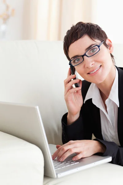 Mujer de negocios acostada en un sofá con un portátil y un teléfono con — Foto de Stock