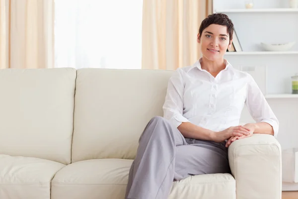 Gülümseyen kadın kanepede oturan — Stok fotoğraf