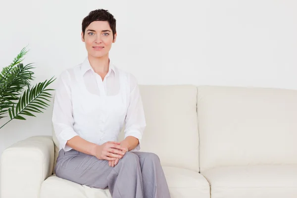 Mulher bonita sentada em um sofá — Fotografia de Stock