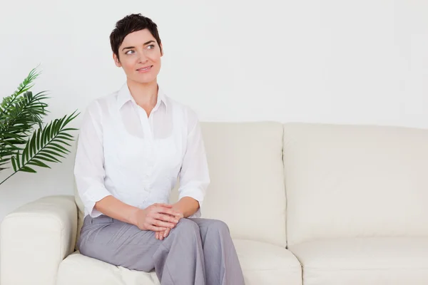 stock image Beautiful brunette woman sitting on a sofa