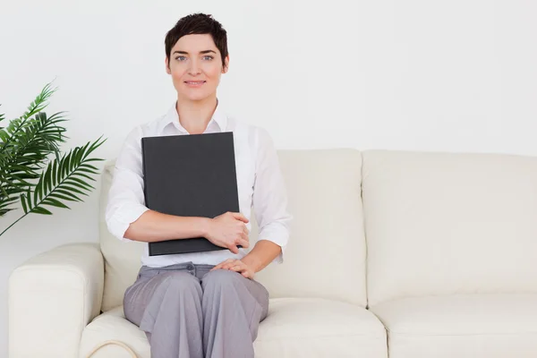 Bruna donna dai capelli corti seduta su un divano — Foto Stock