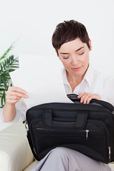 Brunette businesswoman putting some papers in her bag — Stock Photo, Image
