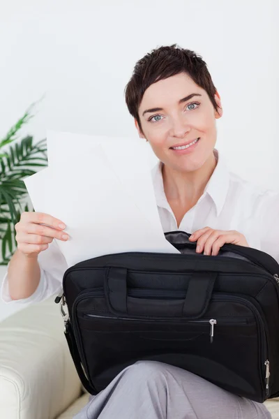 Smiling businesswoman putting some papers in her bag — Stock Photo, Image