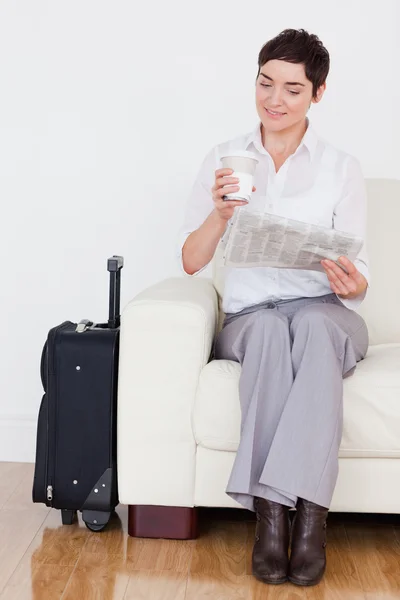 Женщина с чемоданом, телефоном и газетой — стоковое фото