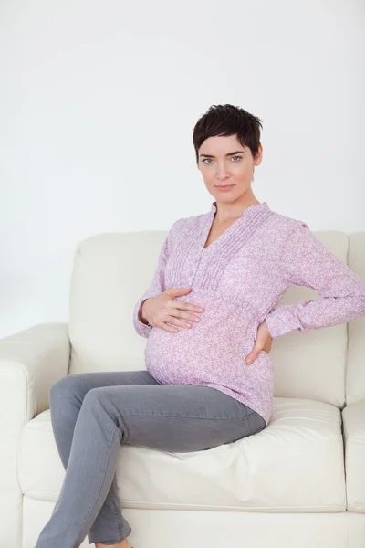 Mulher grávida sentada em um sofá — Fotografia de Stock