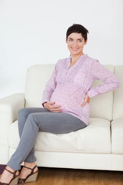 Mulher muito grávida sentada em um sofá — Fotografia de Stock
