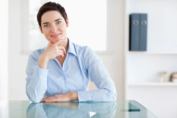 Smiling Businesswoman sitting behind a desk — Stock Photo, Image