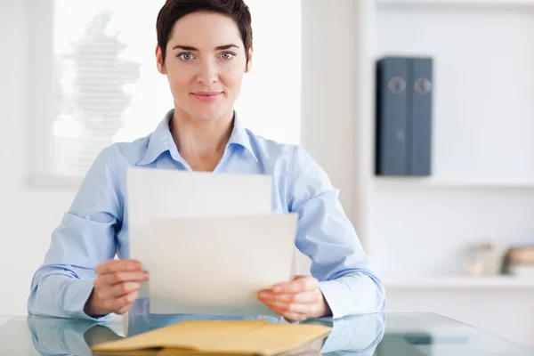 Portrait of a brunette Businesswoman sitting behind a desk with — Stock Photo, Image
