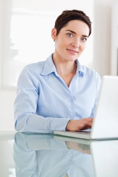 Brünette Geschäftsfrau mit Laptop, die in die Kamera schaut — Stockfoto