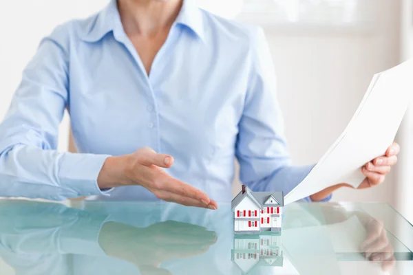 Woman holding papers showing a model house — Stock Photo, Image