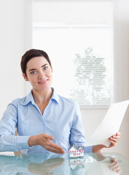 Brunette Woman holding papers showing a model house — Stock Photo, Image