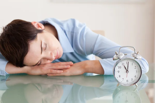 Spanie ładny kobieta z głową na biurku obok alarmcl — Zdjęcie stockowe