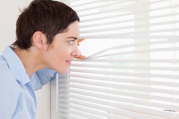 Beautiful woman peeking out a window — Stock Photo, Image