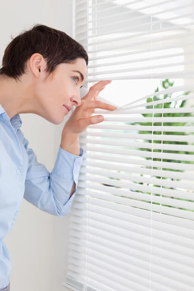 Linda mujer asomándose por una ventana — Foto de Stock