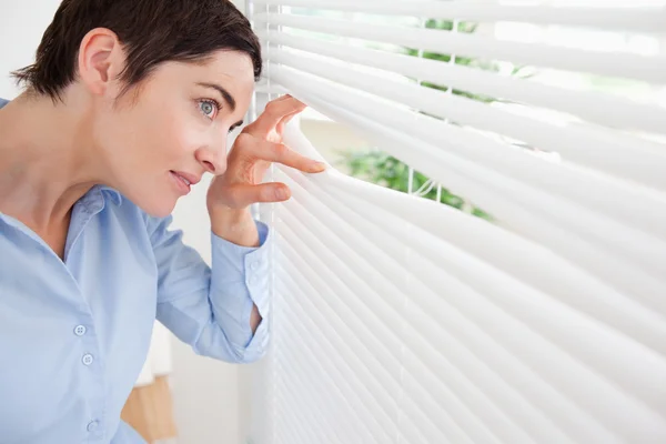 Good-looking brunette woman peeking out a window — Stock Photo, Image