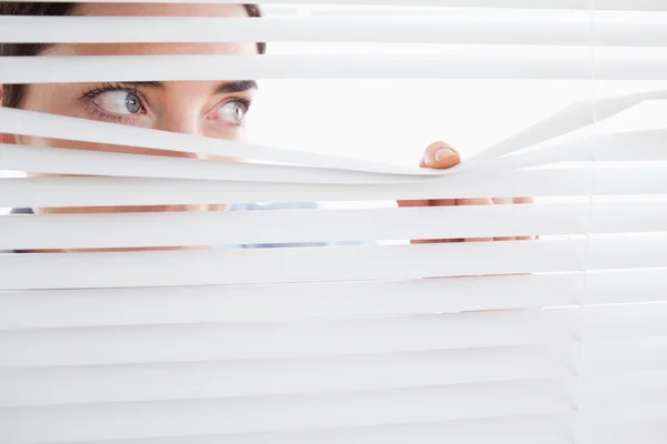 Woman peeking out of a window — Stock Photo, Image