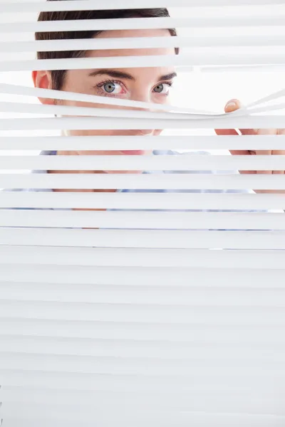 Curious Woman peeking out of a window — Stock Photo, Image