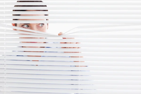 Curious businesswoman peeking out of a window — Stock Photo, Image