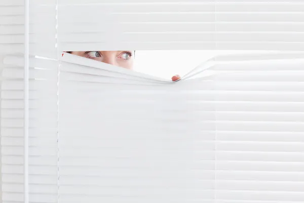 Businesswoman peeking out of a window — Stock Photo, Image