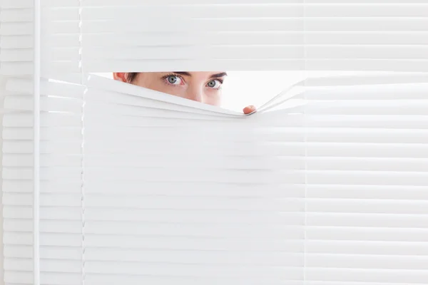 Brunette businesswoman peeking out of a window — Stock Photo, Image