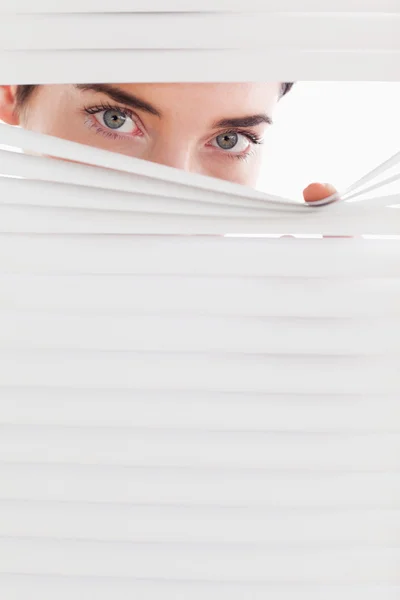 Businesswoman peeking through a venetian blind — Stock Photo, Image