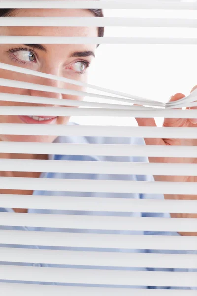 Beautiful businesswoman peeking through a venetian blind — Stock Photo, Image