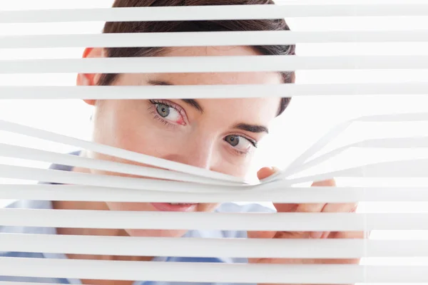 Cute businesswoman peeking through a venetian blind — Stock Photo, Image