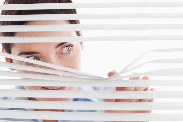 Charming businesswoman peeking through a venetian blind — Stock Photo, Image