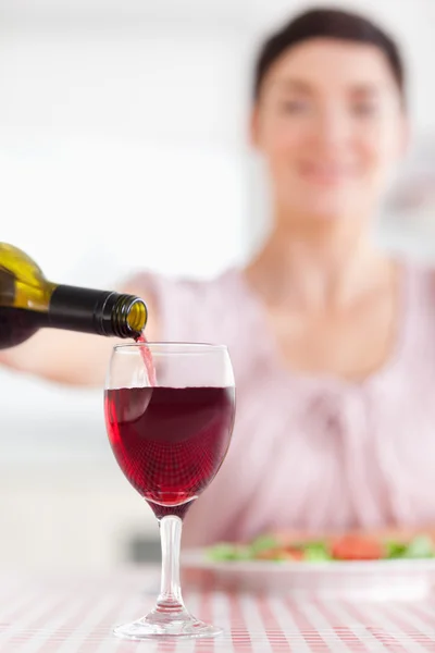 Morena Mulher derramando vinho tinto em um copo — Fotografia de Stock