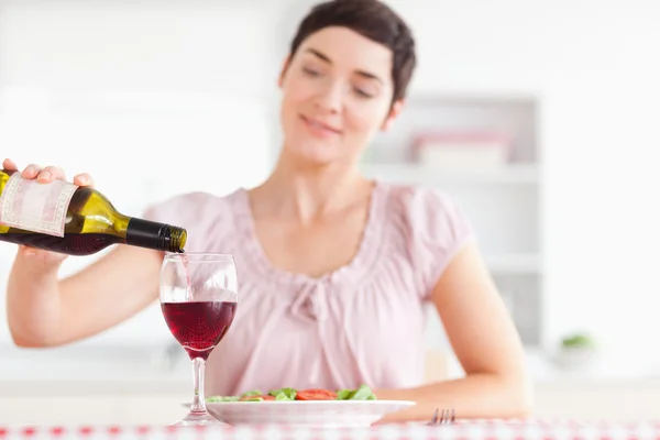 Charmante femme versant du vin rouge dans un verre — Photo