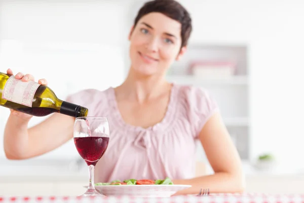 Donna sorridente versando vino rosso in un bicchiere — Foto Stock