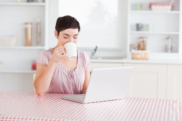 用一台笔记本电脑工作时喝咖啡的女人 — 图库照片