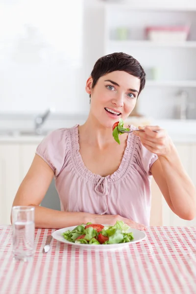 Mulher morena alegre comendo salada — Fotografia de Stock