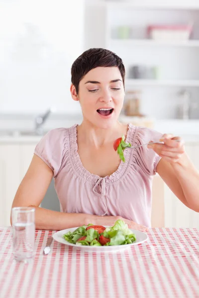 Fröhliche brünette Frau isst Salat — Stockfoto