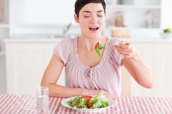 Smiling brunette woman eating salad — Stockfoto