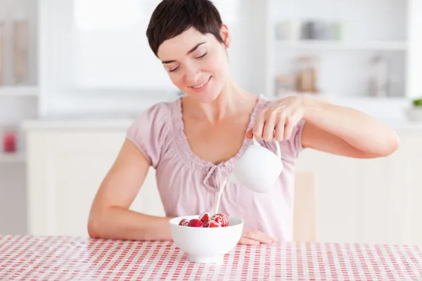Mujer vertiendo crema sobre fresas — Foto de Stock